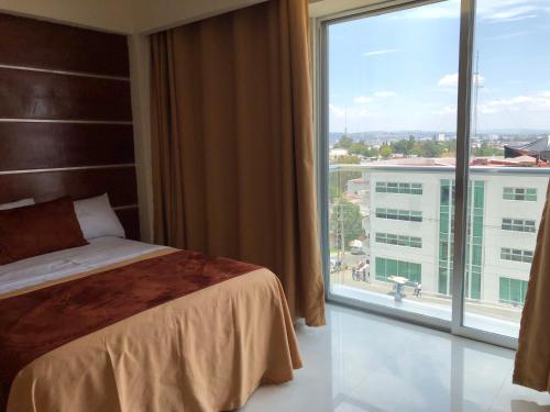a hotel room with a bed and a large window at Hotel Mirto in Puebla