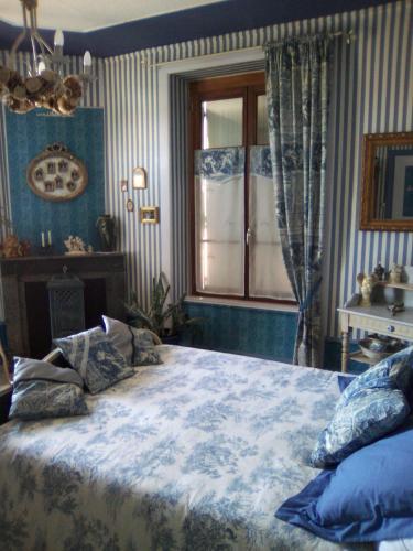 a bedroom with a large bed with blue and white sheets at la Ganse Blanche in Usson-en-Forez