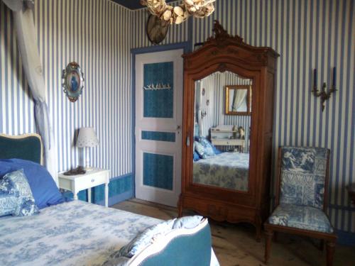 a bedroom with a bed and a mirror and a chair at la Ganse Blanche in Usson-en-Forez