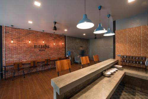 a restaurant with a bench and chairs and a brick wall at Bed & Bike Hostel in Chiang Rai