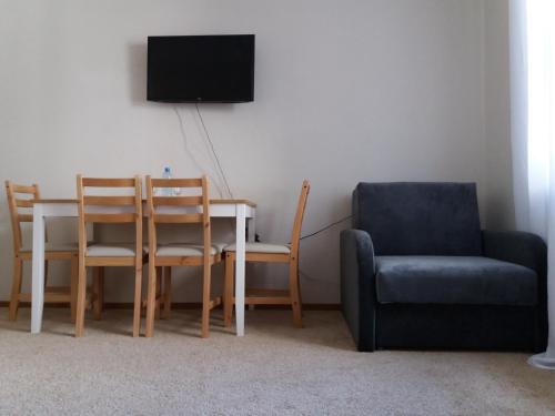 a living room with a table and a chair and a tv at Apartament in Hajnówka
