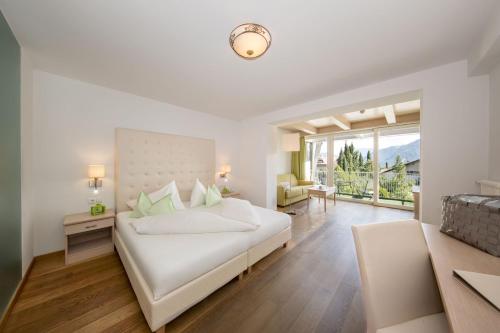 a white bedroom with a bed and a large window at Hotel Weingarten in Appiano sulla Strada del Vino