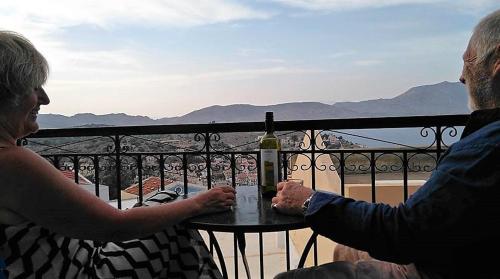 a man and woman sitting at a table with a bottle of wine at Hotel Fiona Symi in Symi
