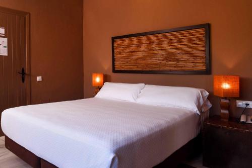 1 dormitorio con 1 cama blanca grande y 2 lámparas en Chillout Hotel Tres Mares, en Tarifa
