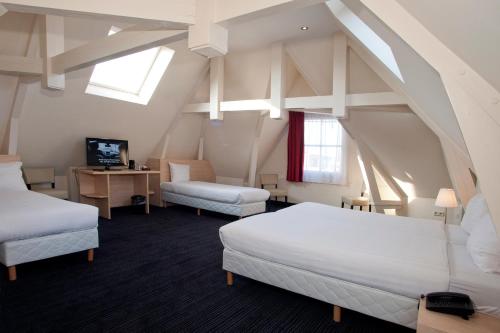 アムステルダムにあるHotel Iron Horse Amsterdamのベッド2台、デスク、窓が備わる屋根裏部屋です。