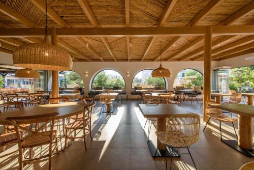 a restaurant with tables and chairs and windows at Aggello Boutique Hotel in Stalida