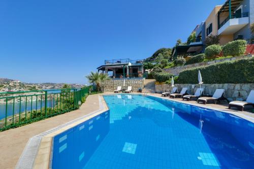 a large swimming pool with chairs next to a building at Erivolos Studios & Apartments in Ligaria