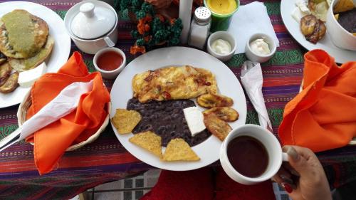 a table with a plate of breakfast food and a cup of coffee at Cristales de Antigua Hotel Cristal in Antigua Guatemala