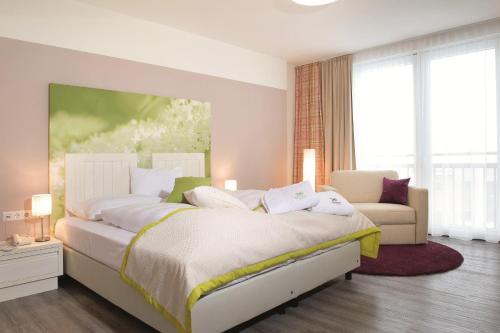 een slaapkamer met een groot bed en een bank bij Hotel Holunderhof in Lienz