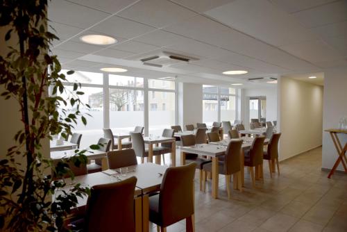 a dining room with tables and chairs and windows at Logis Restaurant & Hôtel À la 12 in Delme