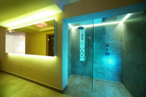 a bathroom with a shower with blue lighting at Hotel Holunderhof in Lienz
