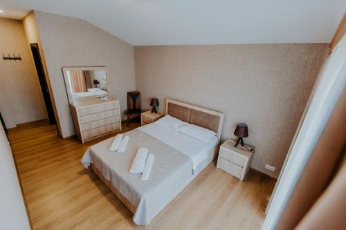 a bedroom with a large white bed and a mirror at Sunset Telavi in Tʼelavi