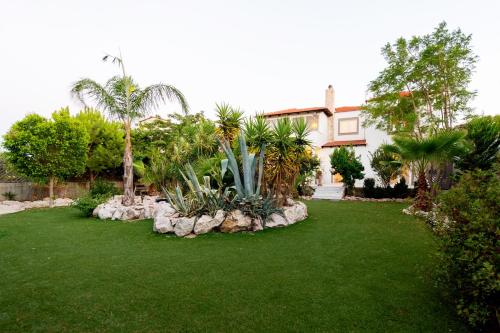 a garden with palm trees and rocks in front of a house at Nicole's garden villa in Kallithea Rhodes
