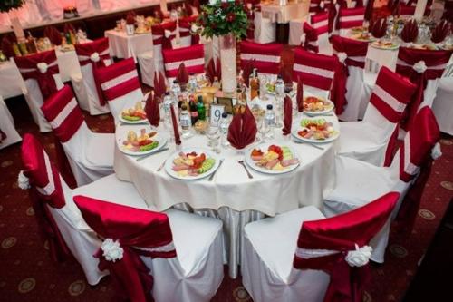 a table with plates of food and red and white chairs at Hotel Rostov in Pleven