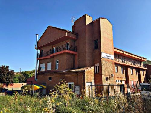 un gran edificio de ladrillo con una valla delante en Albergue Ciudad del Doncel en Sigüenza