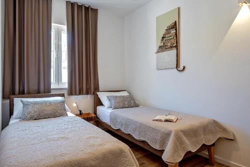 1 dormitorio con 2 camas y ventana en Arka Trogir apartments - Seget Vranjica, en Seget Vranjica