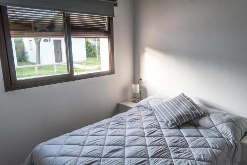 a white bedroom with a bed and a window at Camping Sierra de las Nieves in Yunquera