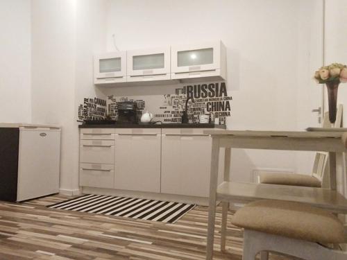 a kitchen with white cabinets and a table and a refrigerator at My Secret Place. in Zielona Góra