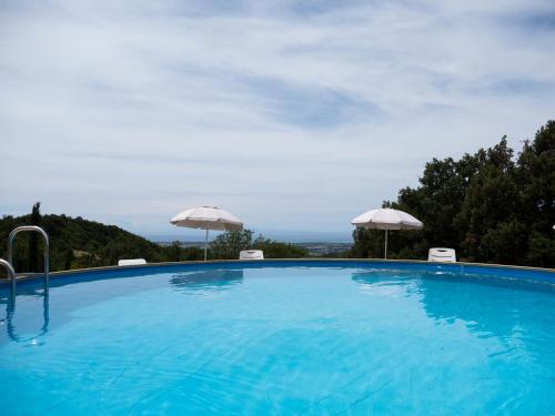 a large swimming pool with umbrellas on top of it at Poderino Bellavista in Castellina Marittima