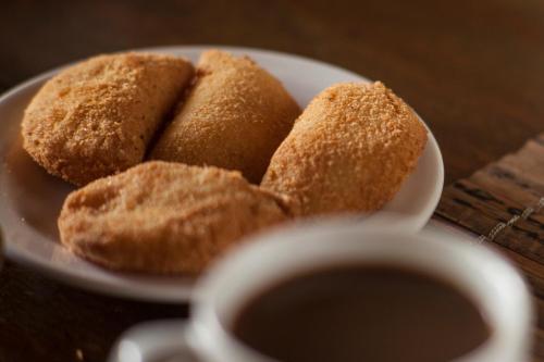 a plate with four donuts and a cup of coffee at Dendê Loft in Ilha de Boipeba