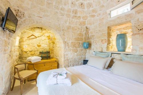 a bedroom with a bed and a chair in a stone wall at Trulli arabesco in Ceglie Messapica