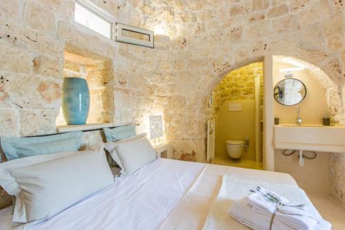 a bedroom with a white bed in a stone wall at Trulli arabesco in Ceglie Messapica