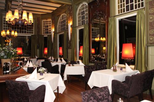 een restaurant met witte tafels en stoelen en kroonluchters bij Augusta Hotel in IJmuiden