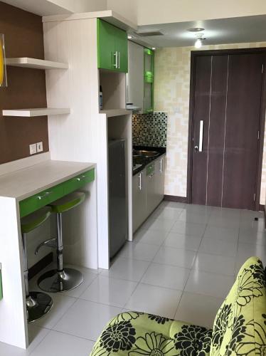 a kitchen with green and white cabinets and a counter at Scientia Residences by Taslim Gading Serpong in Serpong