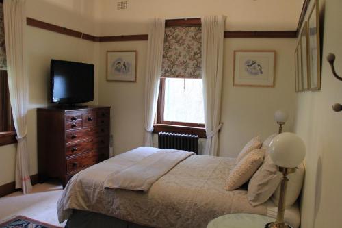 1 dormitorio con 1 cama, TV y ventana en Historic Merryville Homestead, en Murrumbateman