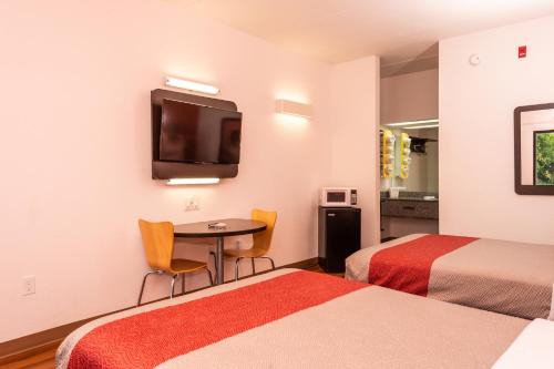 a hotel room with two beds and a table and a tv at Motel 6-Kingsport, TN in Kingsport