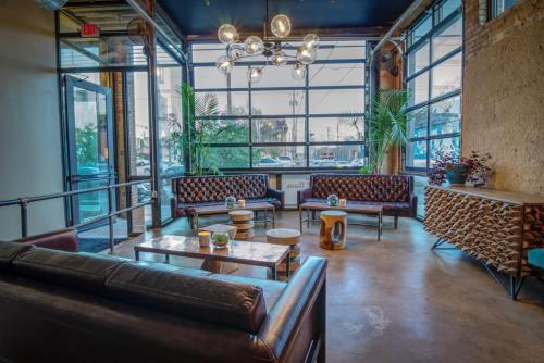 a living room with couches and tables and windows at Deep Ellum Hostel in Dallas