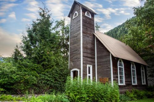 an old church with a tower in the grass at Three Valley Lake Chateau in Revelstoke