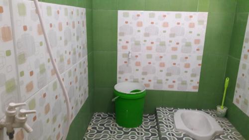 a green bathroom with a toilet and a sink at AAL Homestay in Sabong