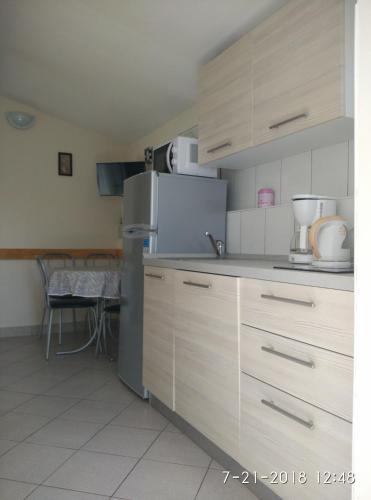 a kitchen with white cabinets and a stainless steel refrigerator at Apartments Gina in Trogir