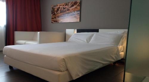 a white bed sitting in a room next to a wall at Best Western Parco Paglia Hotel in Chieti