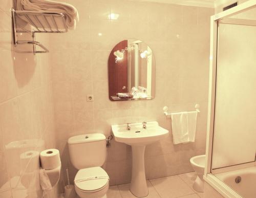 a white bathroom with a toilet and a sink at Hotel El Emigrante in Villanueva de la Serena