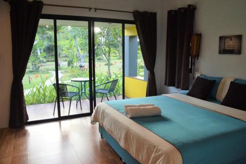 a bedroom with a bed and a balcony with a table at Nubdao Resort&Restaurant in Nong Prue