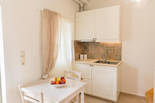 a white kitchen with a bowl of fruit on a table at Romantic house Priotissa II in Tympáki
