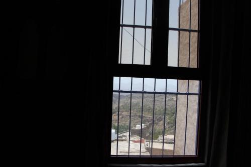 an open window with a view of a building at Durrat Al-Misfah Guest House in Misfāh
