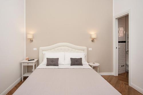 a white bedroom with a large white bed with two pillows at Luxury & Charme Colosseo in Rome