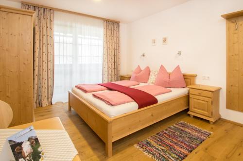 Schlafzimmer mit einem Bett mit rosa Kissen und einem Tisch in der Unterkunft Ferienhof Hinterstrasser in Mondsee