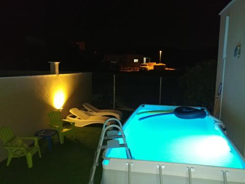 a swimming pool at night with chairs and a lamp at Switzerland In The Arbel in Arbel