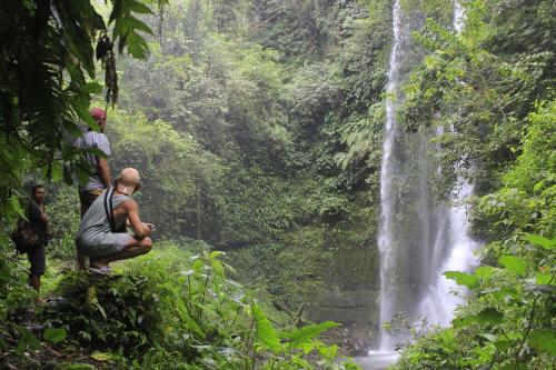 two people standing in front of a waterfall at Kondo Villa in Labuhan Pandan