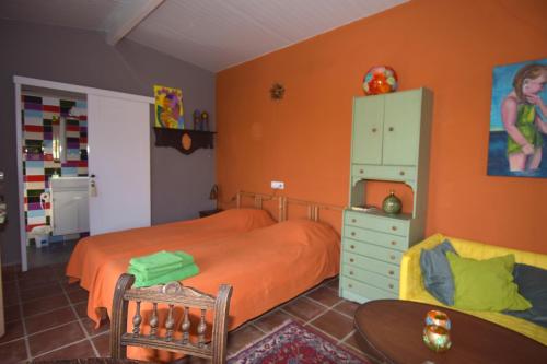 アラウリン・デ・ラ・トレにあるCasita Adelfaのベッドルーム(オレンジ色のベッド1台、テーブル付)