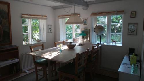 uma sala de jantar com mesa, cadeiras e janelas em GOGGE's HUS em Tisvildeleje