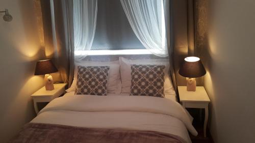 a bedroom with a bed with two lamps and a window at Royals Flower Apartments III in Krakow