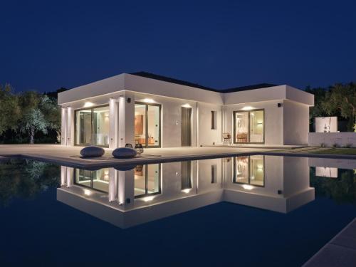 a modern house with a pool at night at Drallos Luxury Villa - Private Heated Pool & Large Groups, by ZanteWize in Alikanas
