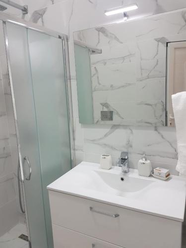 a white bathroom with a sink and a mirror at Vila Alikaj in Sarandë