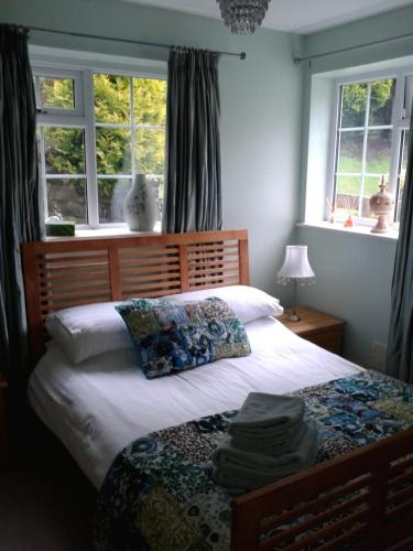 a bedroom with a bed with white sheets and windows at Railway Cottage in Cardiff