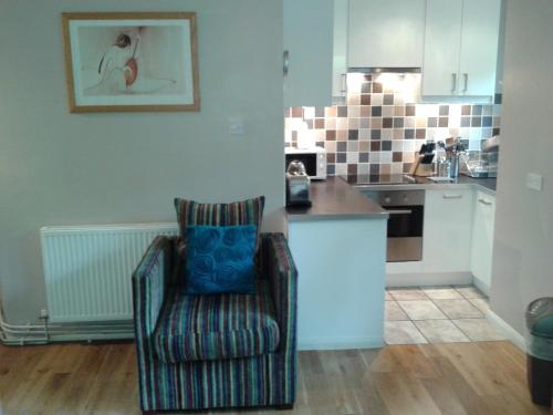 a living room with a chair and a kitchen at Railway Cottage in Cardiff